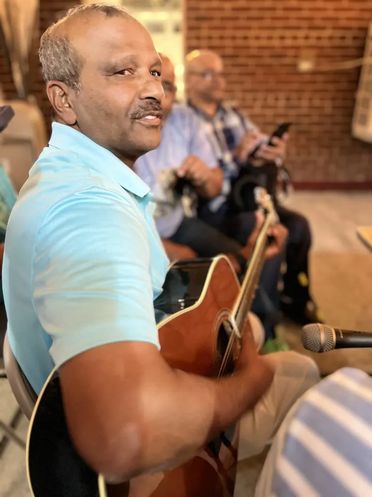 Kris Persaud playing guitar with friends